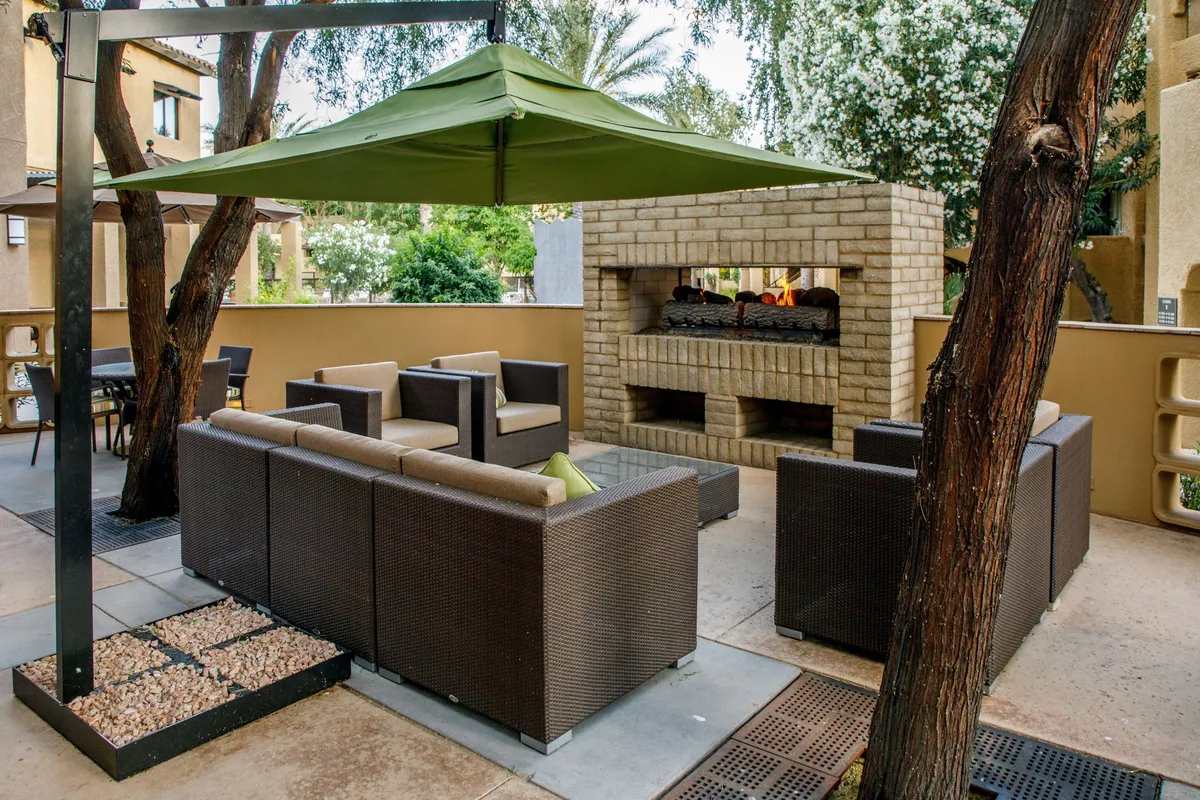 A stylish outdoor lounge area featuring a cozy seating arrangement, a fireplace, and a canopy overhead. This space is perfect for group gatherings, relaxing evenings after a day of golf, or outdoor dining under the stars.