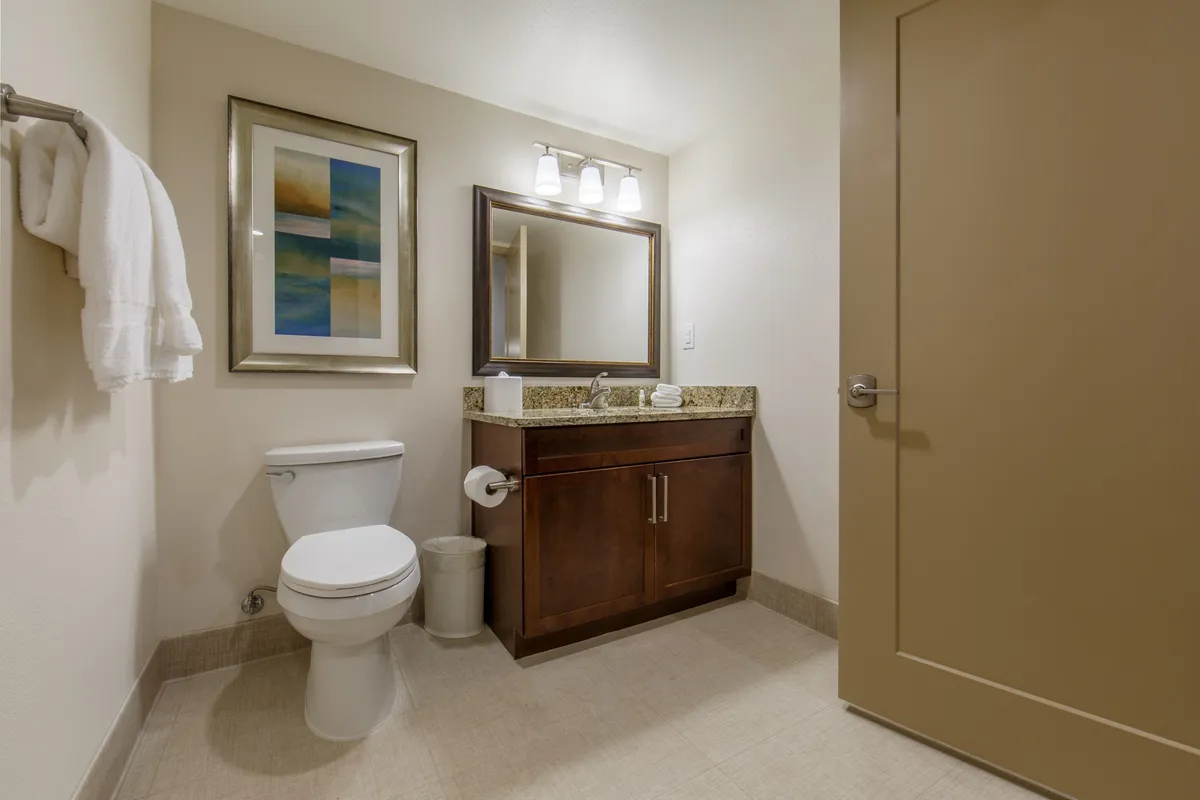 This image showcases a serene bathroom vanity area featuring a granite countertop, framed artwork, and a large mirror. The mood is calming, suggesting a peaceful retreat to refresh after a day exploring Scottsdale or enjoying group activities.
