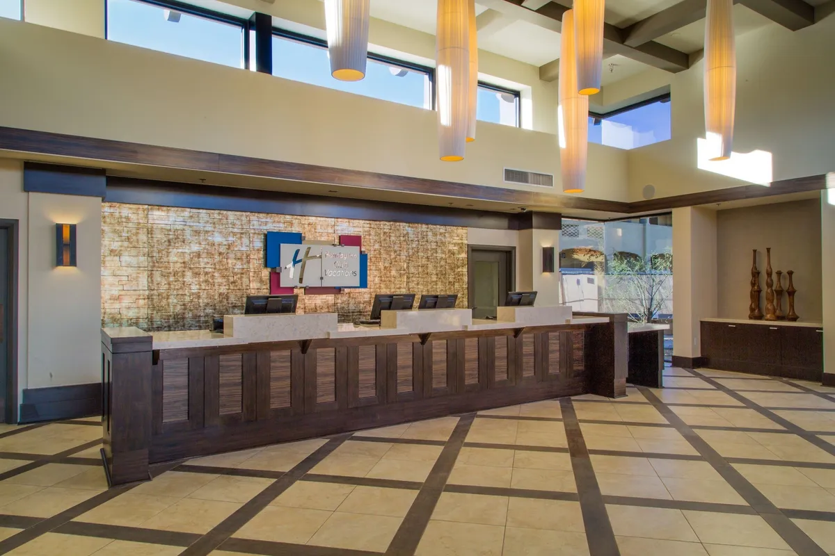 A bright and welcoming interior view of the resort's guest services area, featuring a modern reception desk, stylish artwork, and warm lighting. Guests are seen checking in and interacting with friendly staff, setting a tone of hospitality and convenience.