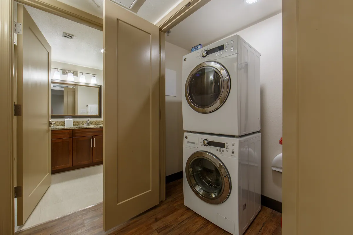 A practical interior scene featuring a stacked washer and dryer alongside a bathroom vanity and mirrored cabinet. The space is organized and functional, ideal for extended stays or group getaways where laundry facilities are appreciated.